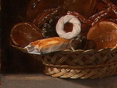 Bodegón español mostrando cesta de mimbre con diversos dulces, destacando un sobao pasiego y una rosquilla