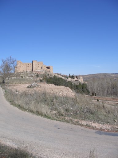 Una vista de la curva del camino que conduce al Oasis, con una zona de tierra removida con un cúmulo de piedras en su centro, que representa la parte superior del talud de la escombrera. Al fondo, la ciudad de Sigüenza