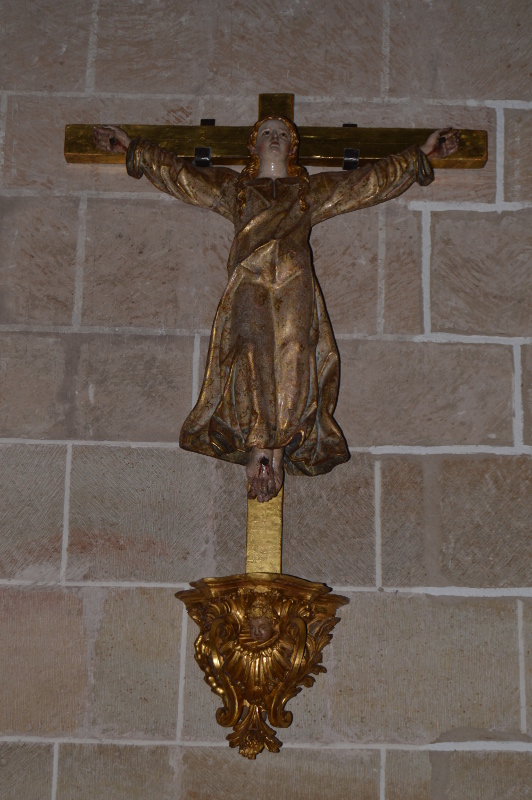 Santa Librada crucificada con tres clavos, vista elevada al cielo, cabellera rubia y amplia túnica dorada 