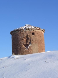 El molino conocido como "El Polvorín" de forma circular, muros de sillería roja, en un paisaje nevado