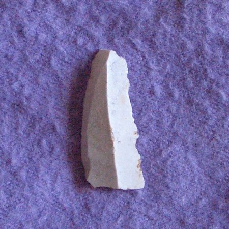 Fragmento de cuchillo de piedra de silex de color blanco, alargado y estrecho. Despuntado