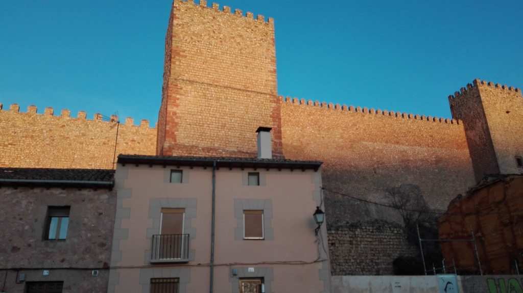Frente de casas de baja altura con los imponentes muros del castillo tras las mismas
