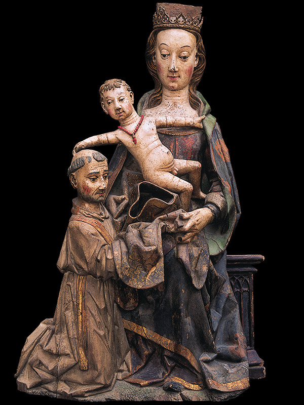 Conjunto en el que aparecen tres figuras: la Virgen María sentada, con el Niño Jesús de pie en su regazo que juguetea con la cabeza de San Ildefonso, que arrodillado recibe la casulla que le da la Virgen