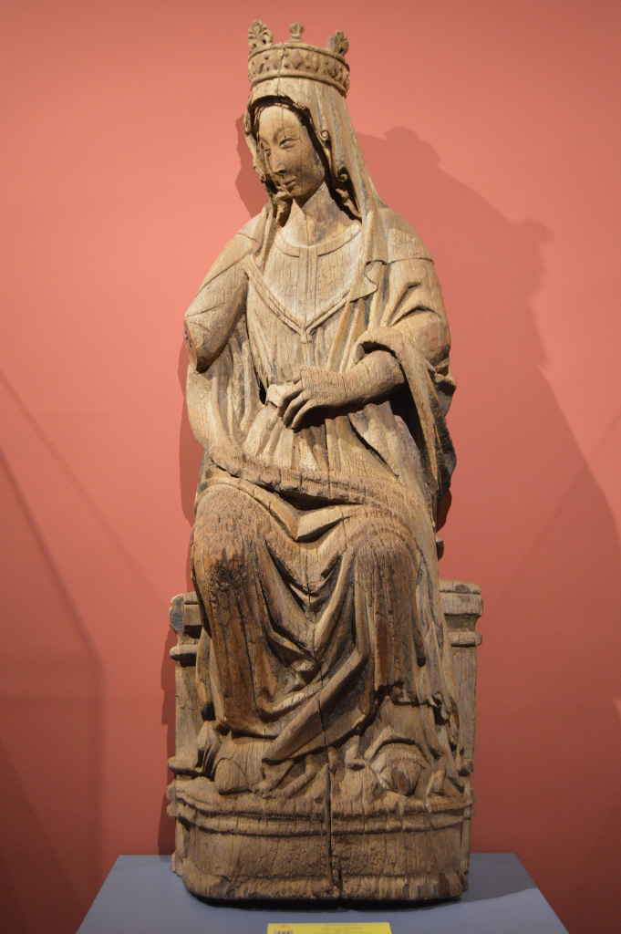 Imagen en madera de la Virgen María entronizada, sentada y cubierta con corona, que gira su torso para dirigir su mirada a su izquierda